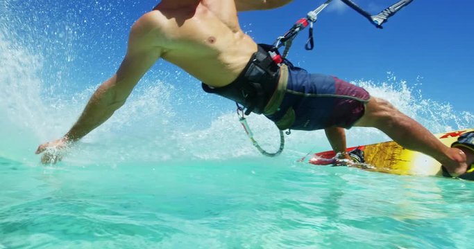 Young man kitesurfing in tropical blue ocean, extreme sport slow motion