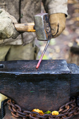 Blacksmith forges hot steel rod with sledgehammer