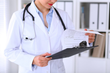 Close-up of a female doctor is filling  out application form or medical history