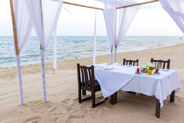 Romantic dinner table for three at a sandy beach in Thailand