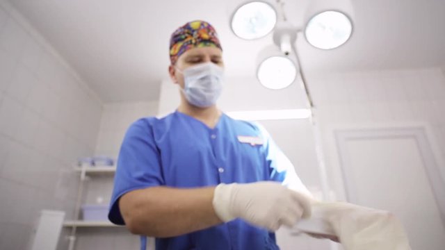 Doctor putting on medical glove in operating room
