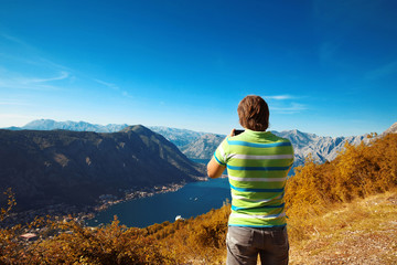 Naklejka premium Kotor. Montenegro. Back view of young man tourist taking photo o