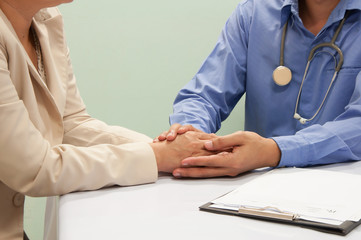 medical doctor holing  patient's hands and comforting her