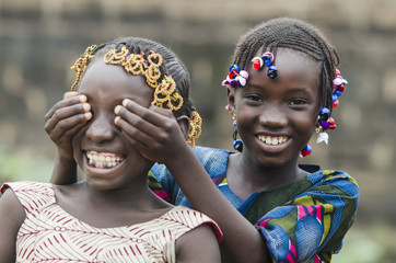 African Girls Playing Peekaboo Outdoors Laughing and Smiling Together (Happiness Symbol)
