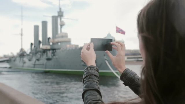 Girl taking photos of Cruiser Aurora St. Petersburg