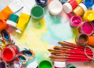 Paints, brushes and palette on the colorful background. The workplace of the artist. Banner for school
