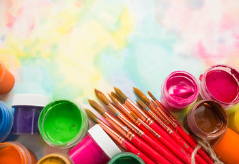 Paints, brushes and palette on the colorful background. The workplace of the artist. Banner for school