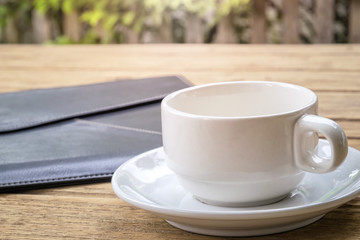 hite coffee cup and leather document envelope.