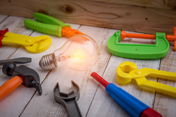 light bulb and tools in front of wood wall.