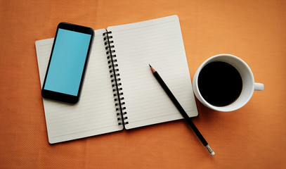 Tea in white cup with Journal book and smartphone