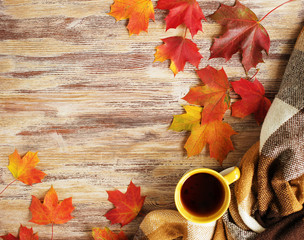 Cup of tea with plaid and leaves on the wood background.