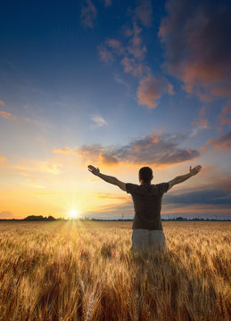Man with raised hands stay in a wheat field