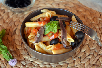 Delicious italian food penne ala puttanesca on a bowl on a table.