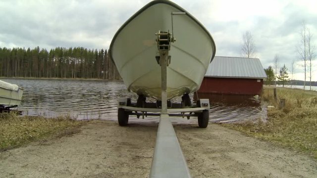 Small boat trailer is moved on a ramp for boat launching