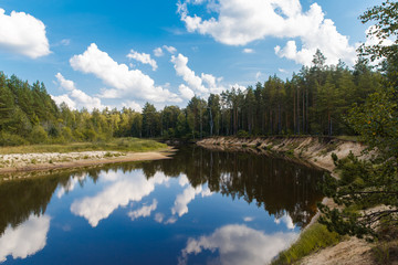 Autumn landscape. The river flows through the forest, blue sky w
