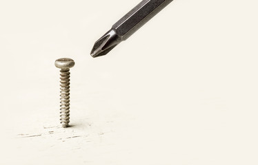 screwdriver and screw on old white wood with copy space, wrong tool for the job idea, put the right...