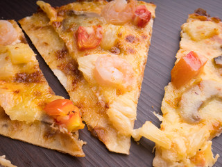 shrimp cocktail pizza with tomato and pineapple on brown wood table