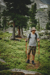 Fototapeta na wymiar Hiker young man with backpack and trekking of cliff and looking