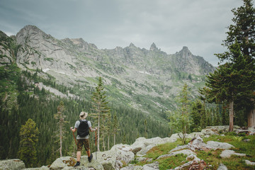 Hiker young man with backpack and trekking of cliff and looking