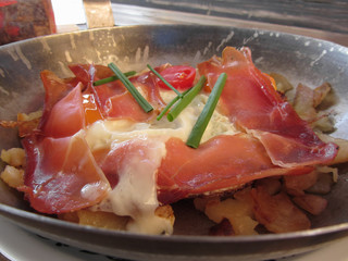 Typical South Tyrolean dish served pan fried with speck, mountain cheese, eggs, potatoes and chive