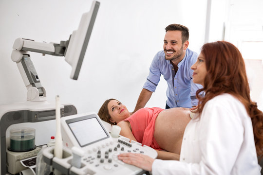 Happy and young couple looking at ultrasound results with doctor