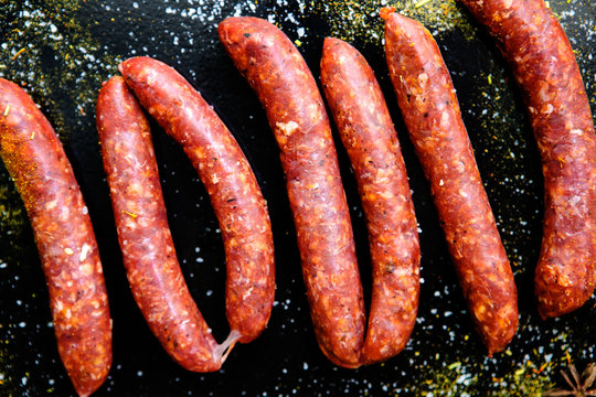 Fresh sausages merguez on a black background, top view, close-up