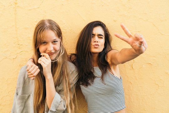 Teen girlfriends posing on yellow background