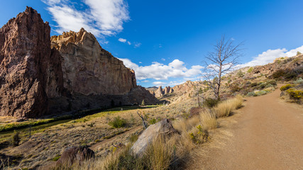 The road among the dry grass. The beautiful landscape of cliffs. Smith Rock state park, Oregon