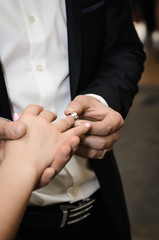 the groom places a gold wedding ring
