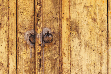 Weathered wooden door with rusty metal knockers