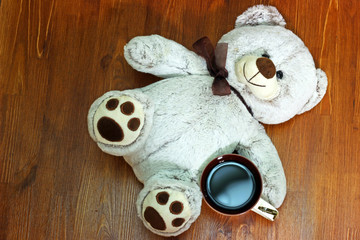 Bear toy with a Cup of black coffee is on the table