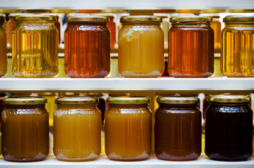 Jars of different honey varieties stocked on a shelf