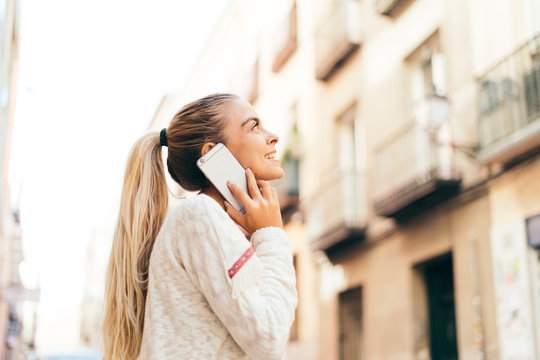 Cheerful Blonde Girl With Tail Talking Over Mobile Phone