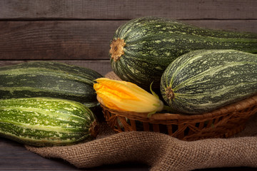 green zucchini or courgettes with a flower on sackcloth wooden background