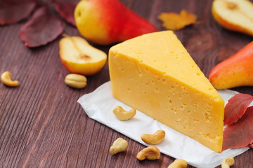 Cheese with pears and nuts on a wooden table