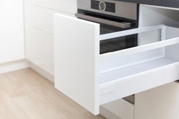 Opened white drawer in a kitchen cabinet with an handleless front, tip to open system