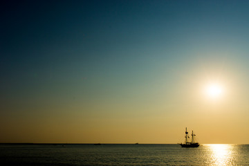 Kleines Schiff am Horizont während Sonnenuntergang