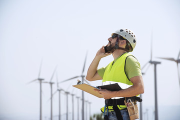 Energy engineer using smart phone at wind farm
