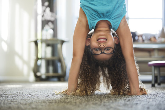 Portrait of girl doing handstand at home
