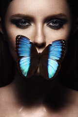 Close up portrait of girl with beautiful makeup. Blue exotic butterfly. Freckled face