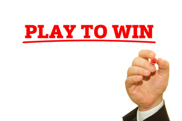 Businessman hand writing PLAY TO WIN message on a transparent wipe board.