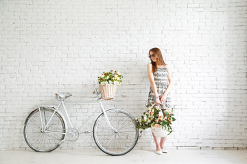 Portrait of a happy beautiful young girl with vintage bicycle and flowers