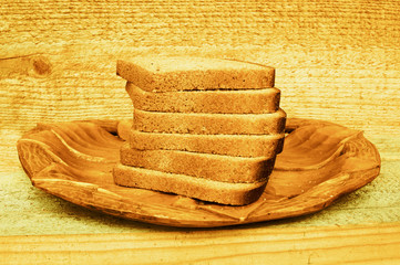 Sliced bread on a carved wooden plate. Wood background