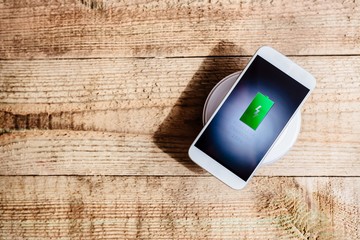 White smartphone charging on a charging pad. © Daniel Jędzura