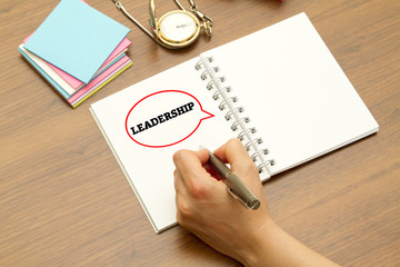 Hand writing LEADERSHIP word on a notebook with pen.