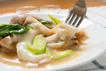 Rad Na, Famous Thai Chinese style wide rice noodle dish with tasty tender pork with thick gravy sauce. close up with fork