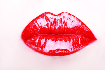 Close-up of woman's lips with bright fashion red glossy makeup.