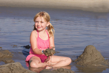 young girl playing in muddy sand