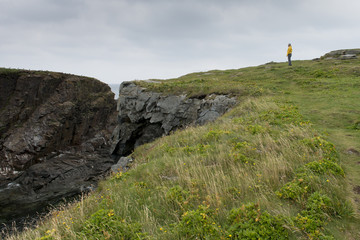 Woman standing on cliff overlooking the ocean, Bonavista Peninsula, Newfoundland, Canada