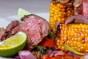 Roast beef with corn, tomatoes and grilled vegetables are on the
